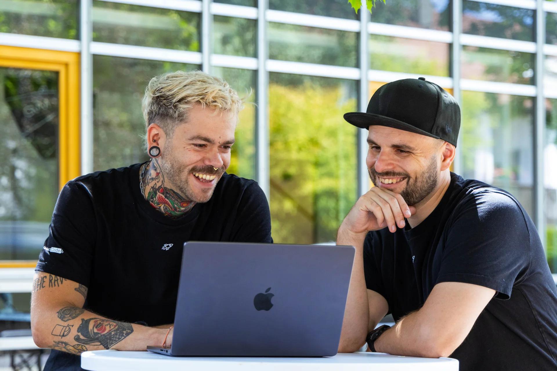 Die meinGPT-Partnermanager Marko und Marc arbeiten gemeinsam an einem Laptop